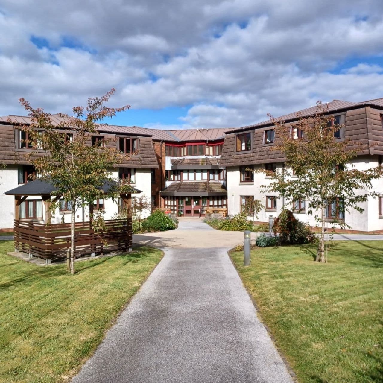 Low-rise residential buildings with dormer roofs around a lawn and central footpath